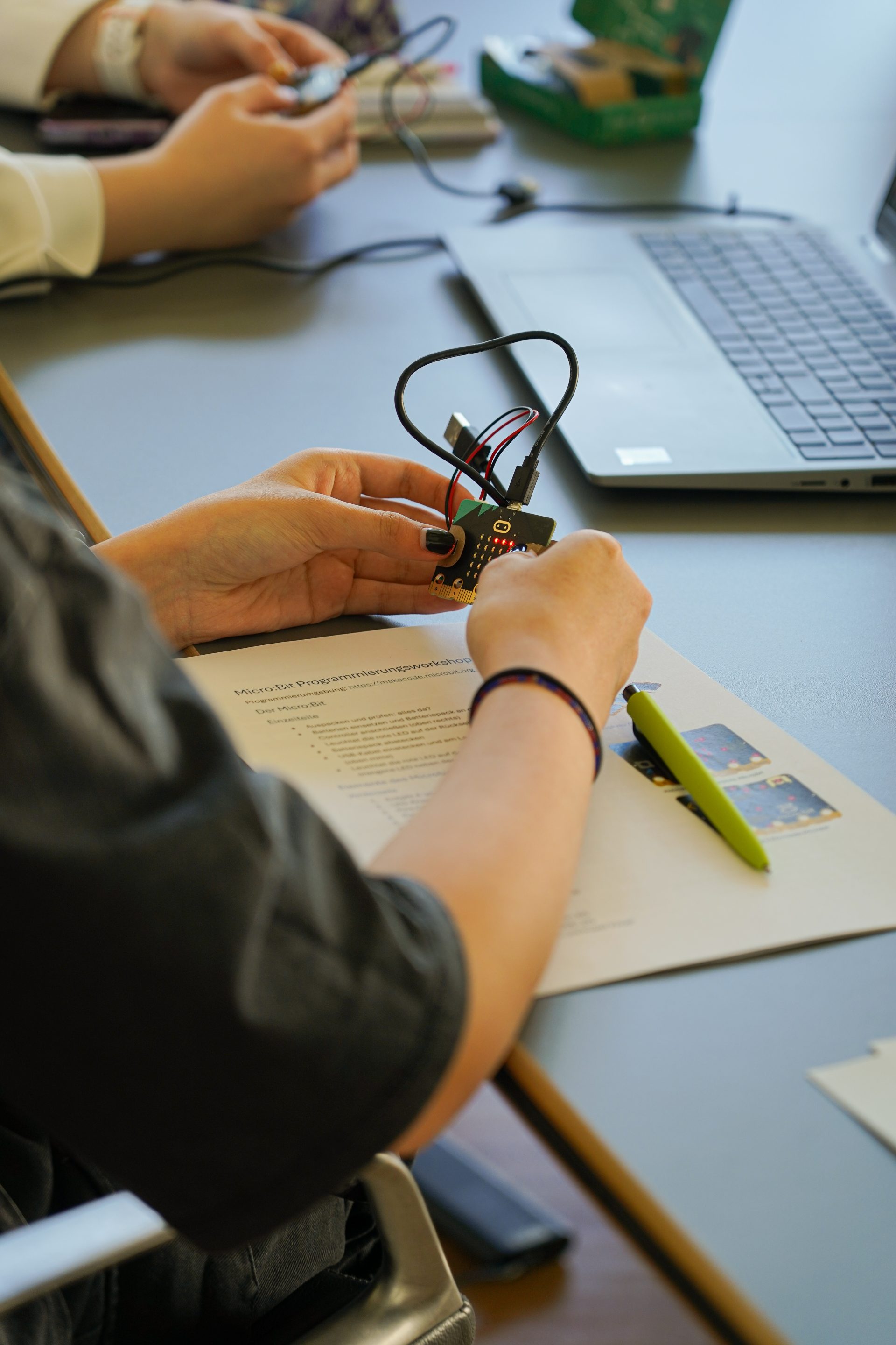 Teilnehmerin beim Girls’ Day 2025 programmiert und testet einen micro bit Controller am Schreibtisch.