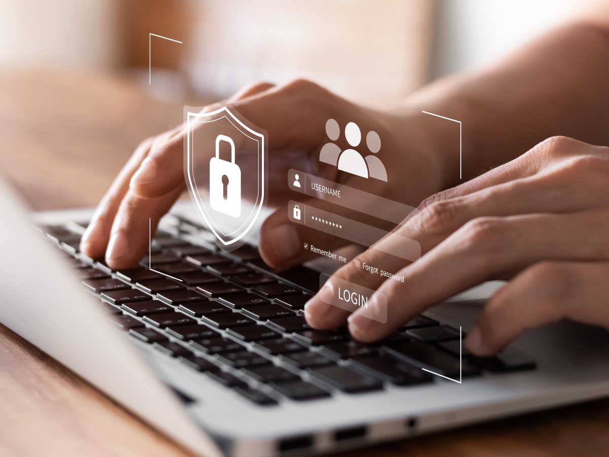 Finger, die auf einem Laptop tippen mit eingeblendeten Symbolen zu Login und IT-Sicherheit